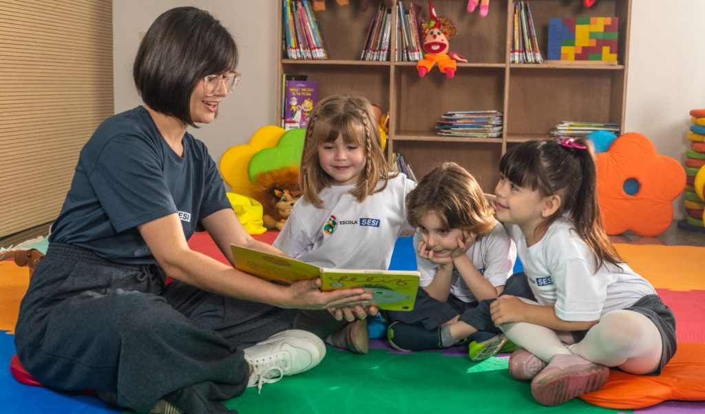 crianças lendo livros com a professora, promovendo a leitura infantil